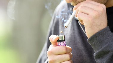 Close up of a teen hands holding a lighter lighting a cigarette ready to smoke