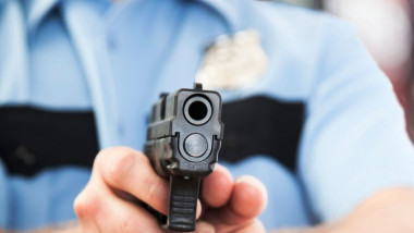 politist care tinteste cu pistolul