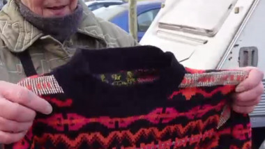 O bătrână arată un pulover pe care vrea să-l vândă