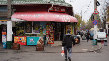 un bărbat cu sacoșă în mână de deplasează spre un magazin de cartier non-stop