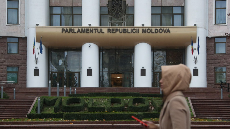 o persoana trece prin fata cladirii parlamentului republicii moldova