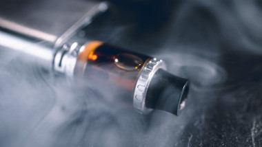 Vape pen metal electronic cigarette with vaping smoke cloud dark background
