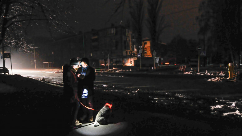 locuitori ai Kievului își plimbă câinele pe o stradă întunecată