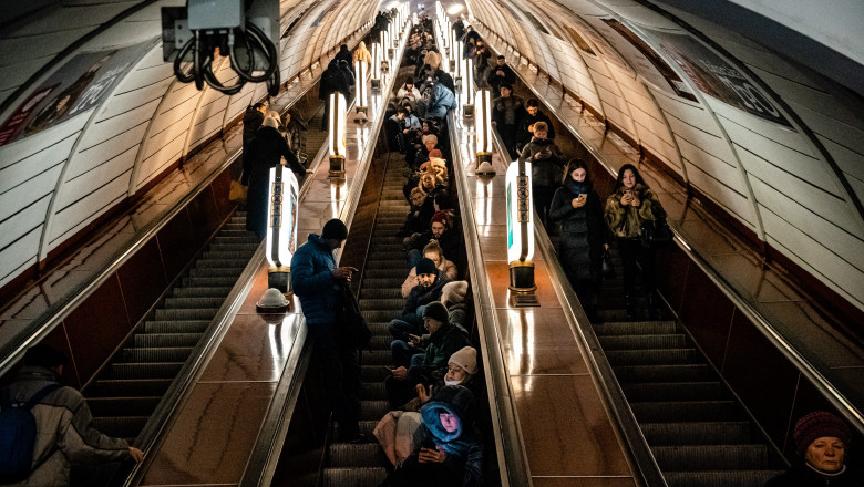 Civilians sit on an escalator while take shelter inside a metro station during an air raid alert in the centre of Kyiv