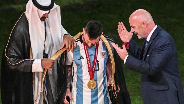 Lionel Messi îmbrăcat într-o mantie neagră de emir în timp ce Gianni Infantino privește