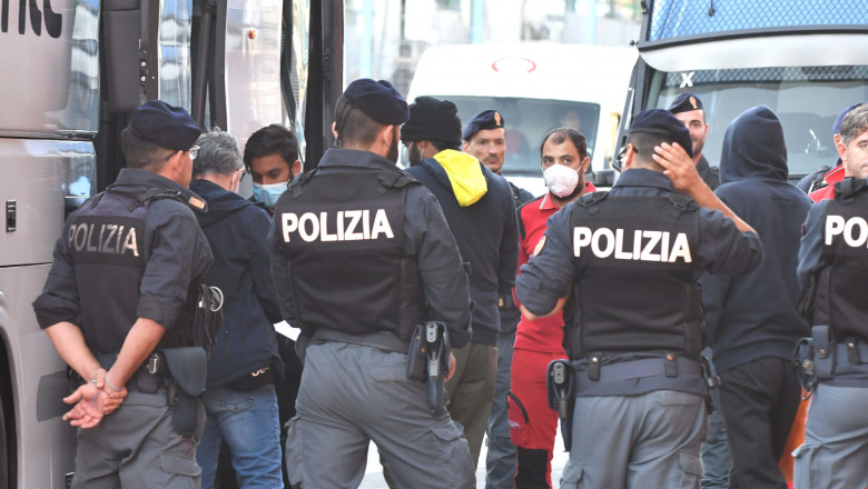 polițiști italieni și migranți lângă un autocar