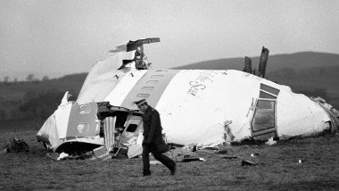Bucăți din botul avionului care s-a prăbușit peste Lockerbie și un bărbat care merge lângă