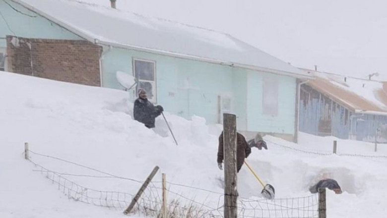 om cu o lopată într-un maldăr de zăpadă înalt cât casa