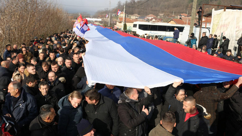 Sârbi kosovari care țin pe mâini un steag al Serbiei