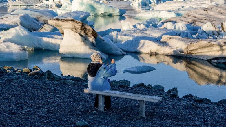 O persoană face fotografii pe malul lacului inghetat Jökulsárlón din Islanda