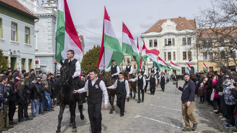 tineri calare si pe jos cu steagul ungariei de ziua maghiarilor, parada la covasna
