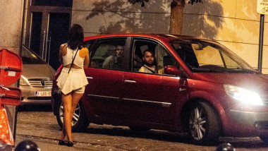 Men in car pass a sex worker on the night time street in Brussels, Belgium