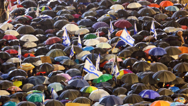 Israelieni cu steaguri și umbrele la protest
