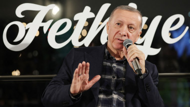 Erdogan gesticulează în timp ce vorbește la microfon