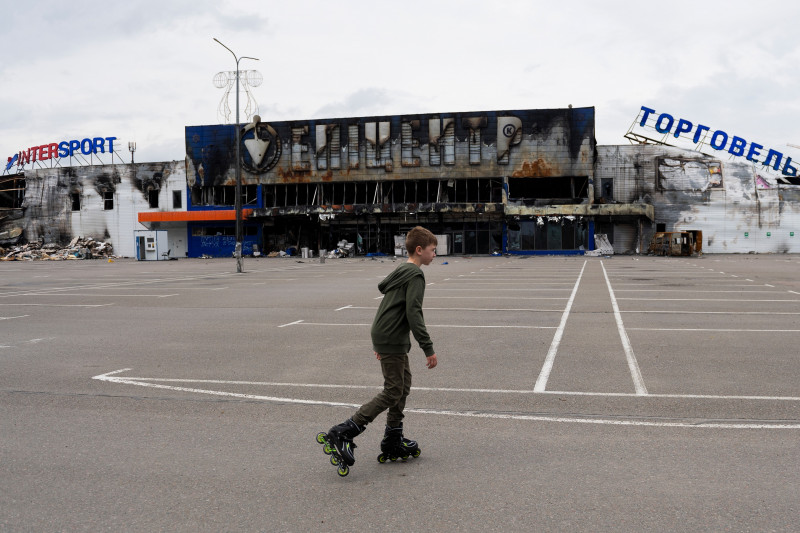 copil care merge pe role pe lângă o clădire distrusă în Ucraina