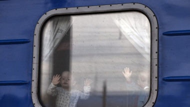 Copii fac cu mâna dintr-un tren cu refugiați ucraineni care părăsesc regiunea Donbas