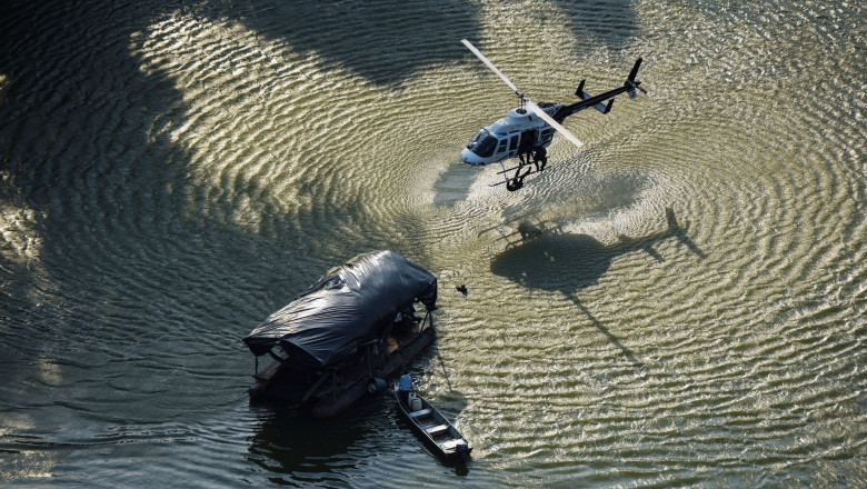 Un elicopter zboară foarte aproape de o barcă pe un râu