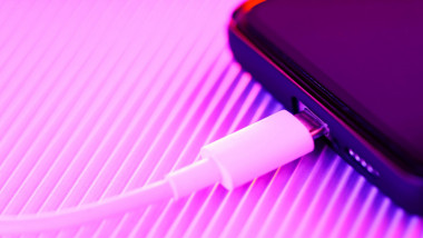 Smartphone charging on a purple background. Mobile phone with connected usb cable for battery charging. Fast charging concept