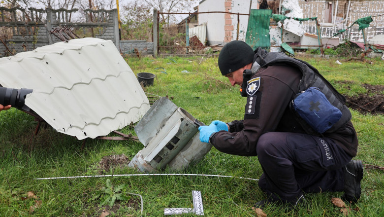 Un anchetator ucrainean pentru crime de război inspectează o rămășiță a ceea ce se crede a fi o bombă cu dispersie în regiunea Herson, care a fost distrusă de rachetele rusești