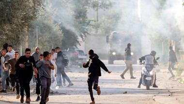Palestinians run for cover during confrontations with Israeli forces in the occupied-West Bank city of Jenin,