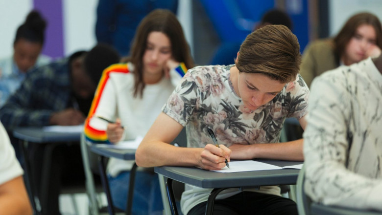 elevi studenti scriu in banci in clasa