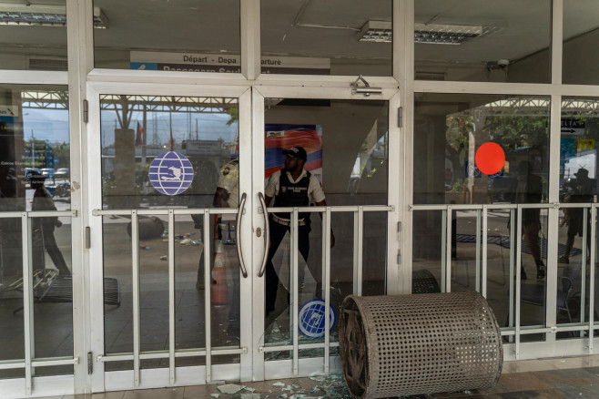 agenți de pază în spatele unui geam spart în aeroportul din haiti