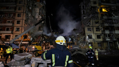 Un pompier priveşte ruinele blocului din Dnipro care a fost distrus de o rachetă