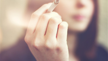 Woman hands holding cigarette outdoor.