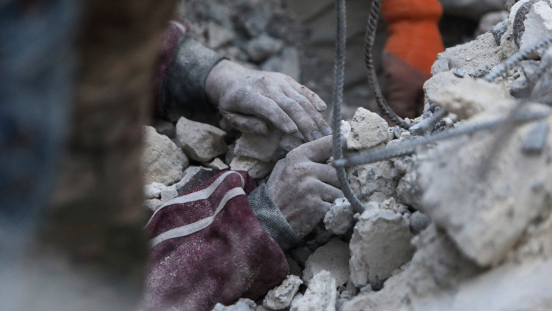 mâinile unui om prins între dărâmături în Siria, după cutremur