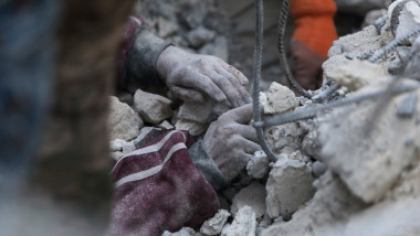 mâinile unui om prins între dărâmături în Siria, după cutremur