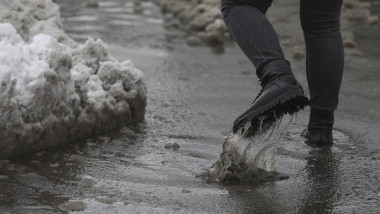 O persoană merge printr-o baltă formată de topirea zăpezii în București.