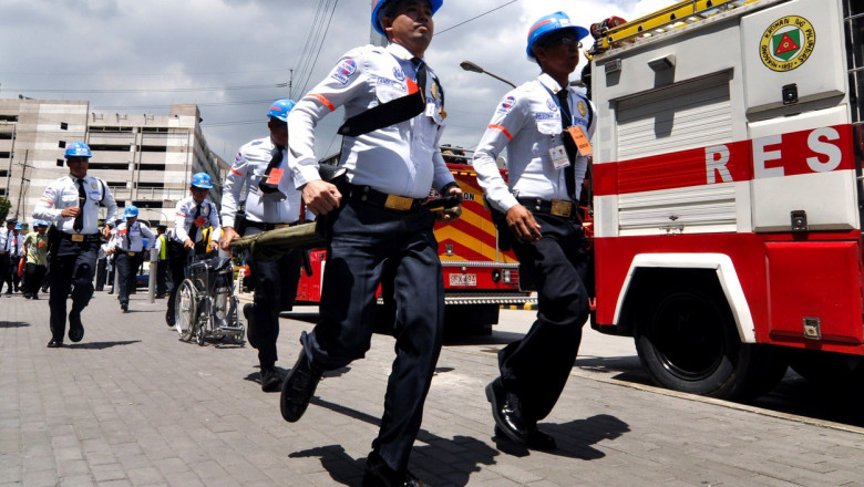 Mai mulți polițiști din Filipine aleargă cu tărgi și scaune cu rotile în cadrul unui exercițiu de intervenție la cutremur.