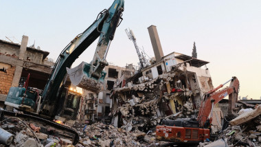 Două utilaje degajează resturile unei clădiri prăbușite la cutremur în Turcia, provincia Hatay, pe 14 februarie 2023.