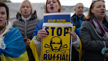 O femeie ţine două postere cu mesajele "opriţi-l pe Putin, opriţi Rusia" în cadrul unui protest din Franţa faţă de invazia Rusiei în Ucraina.