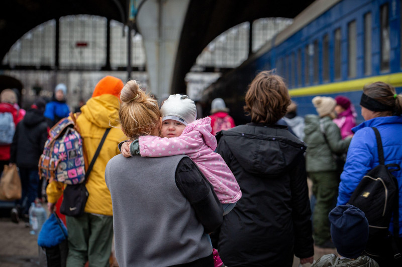 LVIV, UKRAINE - APR 02, 2022: War in Ukraine. Little girl on mom's shoulder. Refugees from the evacuation train from Mariupol, Berdyansk, Kryvyi Rih,