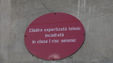 O bulină roșie cu mesajul "Clădire expertizată tehnic încadrată în clasa I risc seismic" montată pe peretele exterior al unei clădiri fotografiată pe 16 februarie 2023.