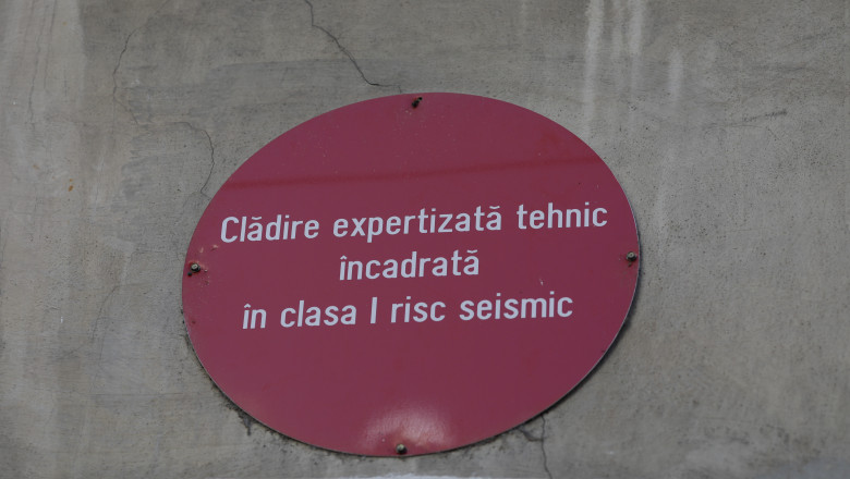 O bulină roșie cu mesajul "Clădire expertizată tehnic încadrată în clasa I risc seismic" montată pe peretele exterior al unei clădiri fotografiată pe 16 februarie 2023.