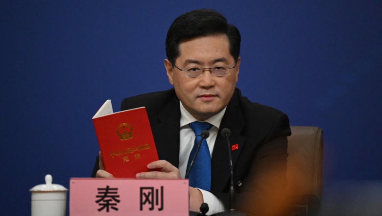 China's Foreign Minister Qin Gang holds a copy of China's constitution during a press conference