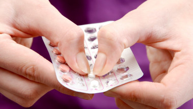 O femeie scoate o pastilă contraceptivă dintr-un flacon.