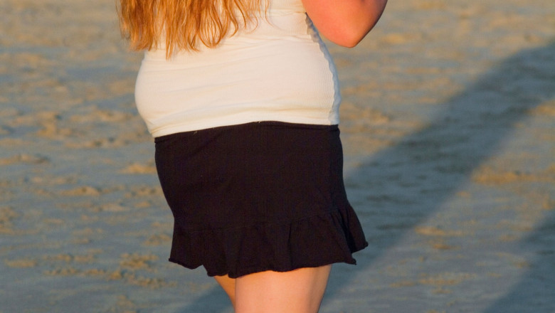 Close up of mid-torso of obese girl walking in a short skirt illustrating unhealthy lifestyle