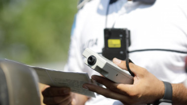 Un agent de poliție ține în mână un aparat de măsurare a alcoolemiei în dreptul unei benzinării de pe Autostrada Soarelui pe 10 august 2021.