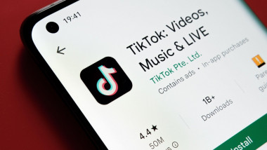 TikTok app seen in Google Play Store on the smartphone screen placed on red background. Close up photo with selective focus. Stafford, United Kingdom,