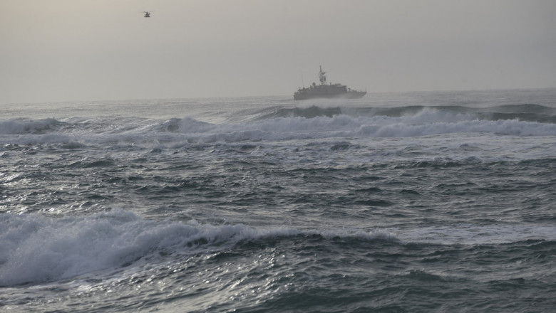 O ambarcațiune și un elicopter văzute din depărtare în Marea Mediterană pe 27 februarie 2023.