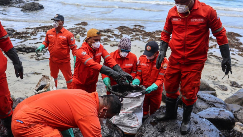 Muncitori stâng păcura deversată pe plajă, pe 8 martie 2023, după ce un petrolier s-a scufundat lângă insula Mindoro.