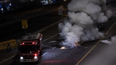 Fire-fighters extinguish a fire after police officers re-opened the Ayalon highway as it was blocked by demonstrators