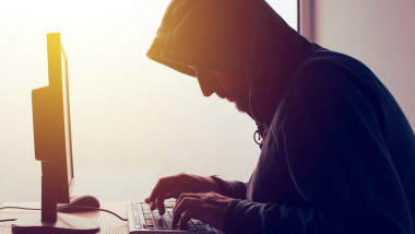 Un hacker stă la calculator.