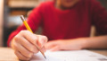 un copil tinand in mana un creion in timpul unui examen