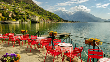 teresa cu scaune si mese rosii pe maul unui lac