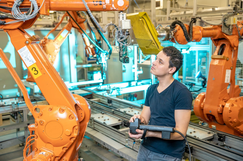 inginer controlează brațe robotice într-o fabrică