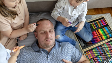 doi copii isi coloreaza pe frunte tatal care doarme